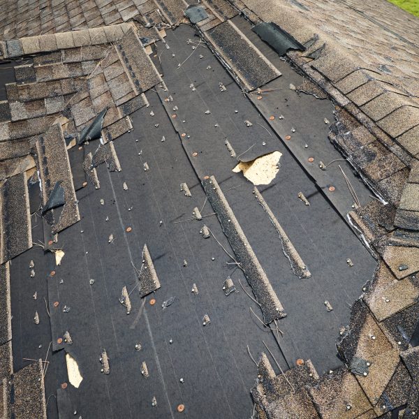 Damaged house roof with missing shingles after hurricane Ian in Florida. Consequences of natural disaster.