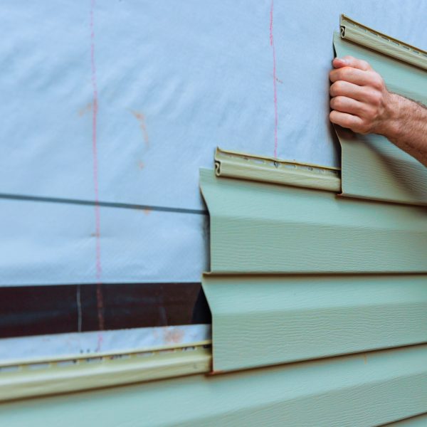 Installation of vinyl siding plastic panels on facade wall new home by an contractor