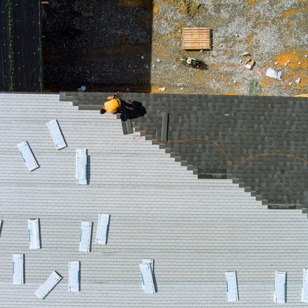 Roofing construction with roofer hands installing asphalt shingles on house the hammer and nails